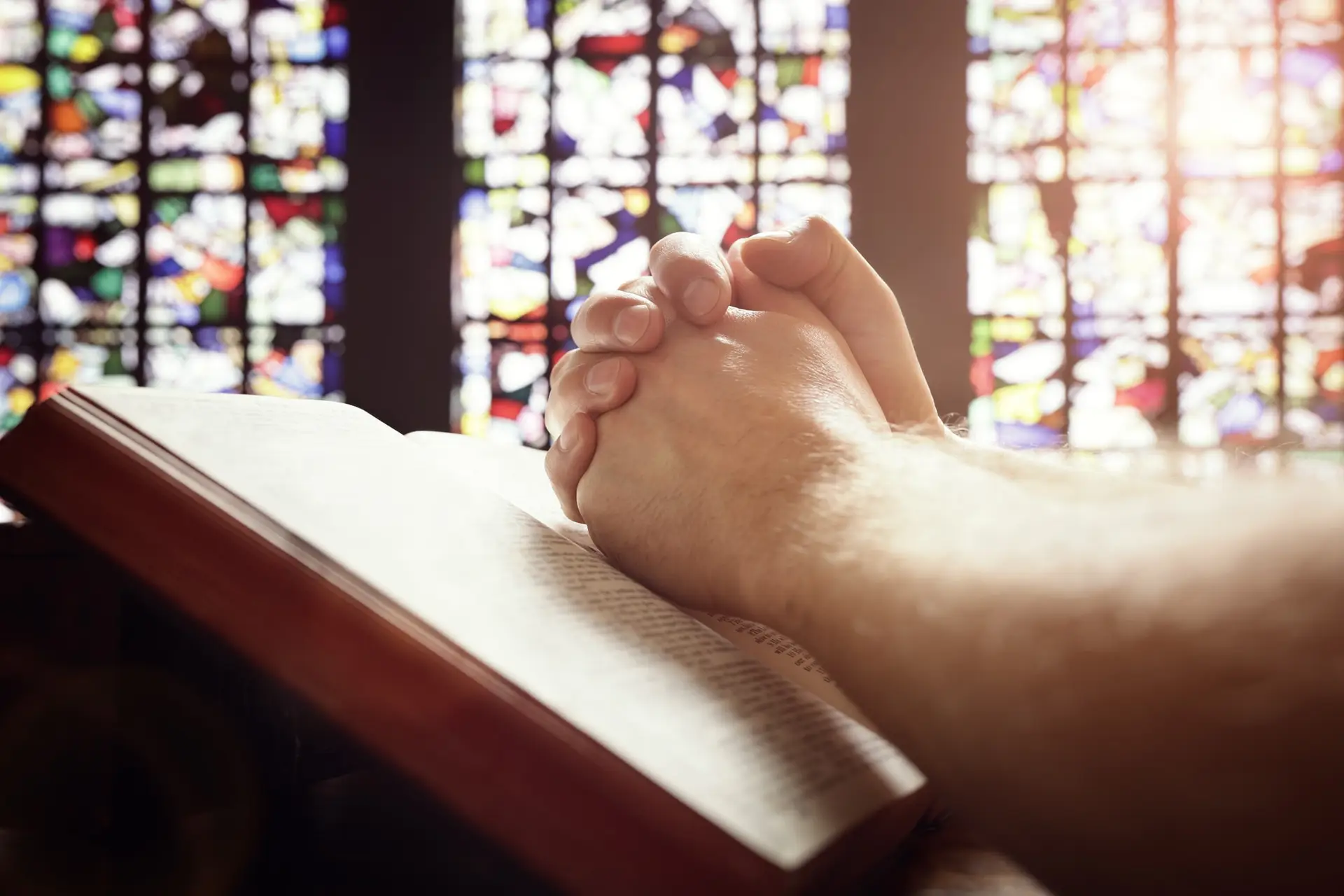 Praying hands on a Holy Bible