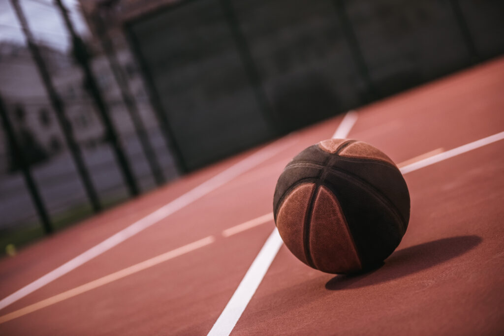 Dark-colored basketball lying on basketball court outside