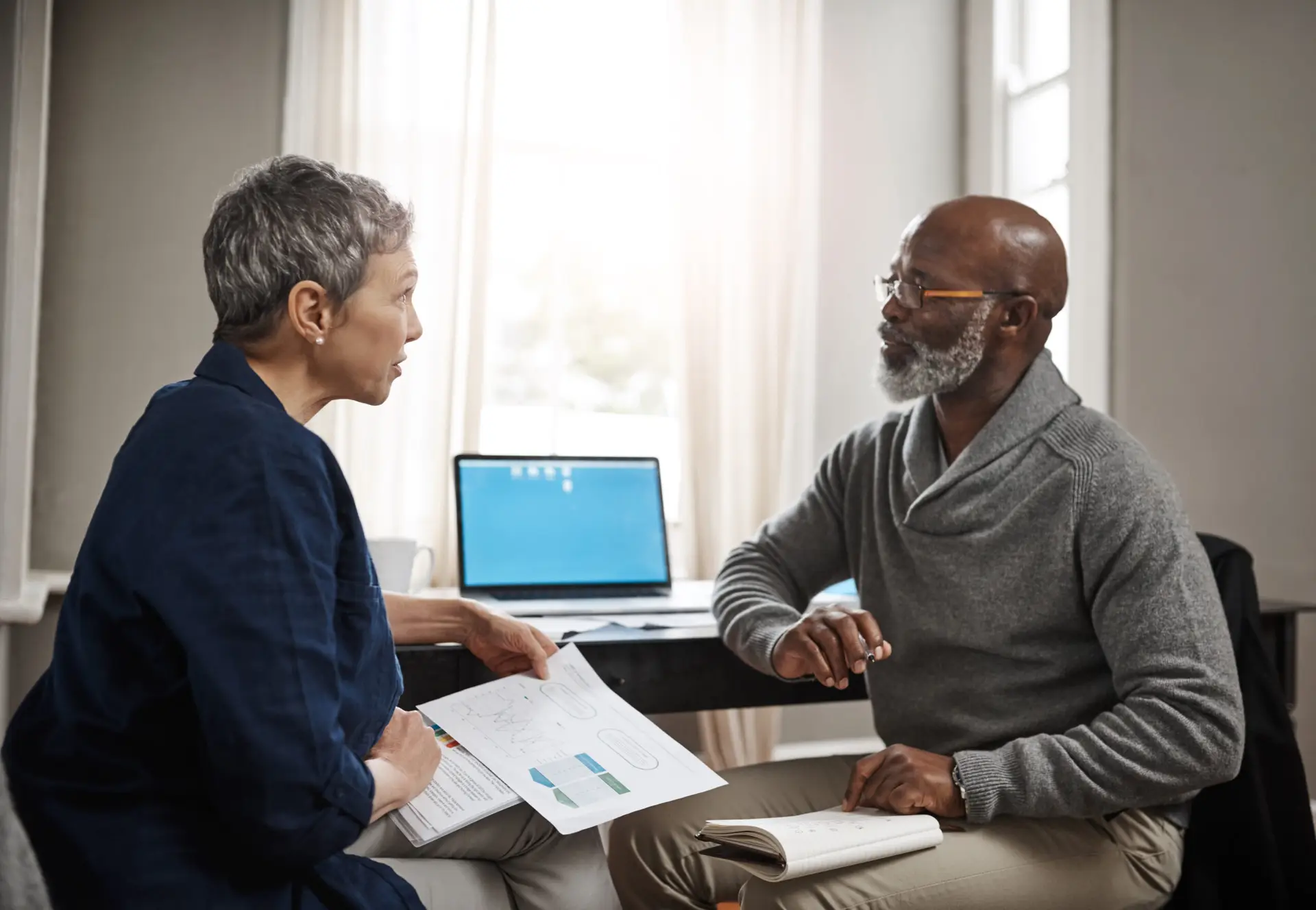 Man and woman sit facing each other, discussing retirement plans